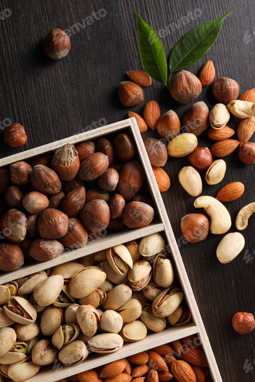Preview: Wooden box with different nuts on a dark background