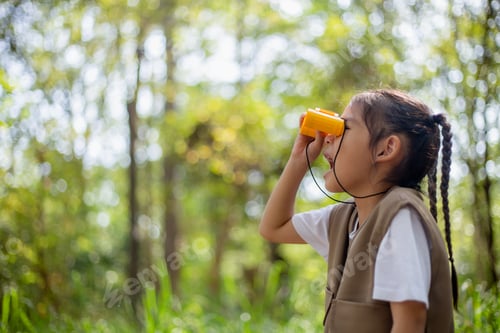 Preview: Happy Little Asian girls looking ahead and smiling child with the binoculars in the park.