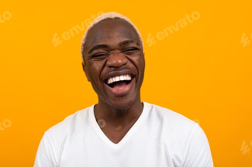 Preview: Closeup portrait of a smiling handsome black blond African man on an orange studio background