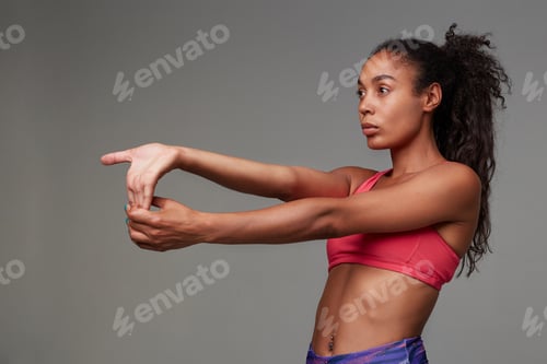 Preview: Back view of young sporty dark skinned curly long haired brunette woman stretching