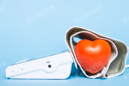 Preview: Red heart and white electronic tonometer isolated on a blue background