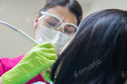 Vista previa: Female dentist cleaning teeth of patient
