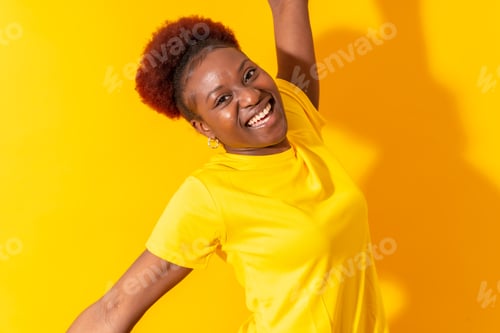 Preview: Young african american woman isolated on a yellow background smiling and dancing, studio shoot