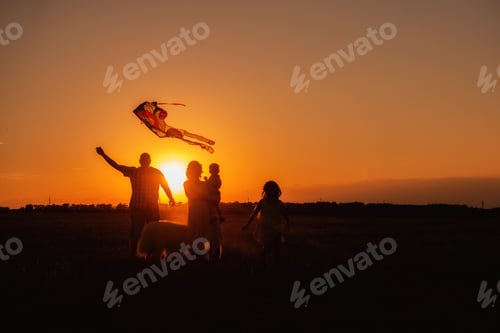 Preview: Panorama silhouette diversity family with Samoyed running at sunset with kite in sky.