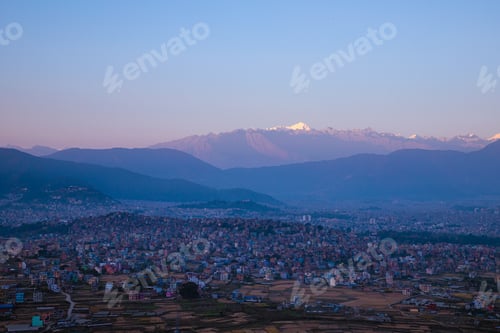 Preview: Densely Populated City Surrounded by Mountains at Sunrise