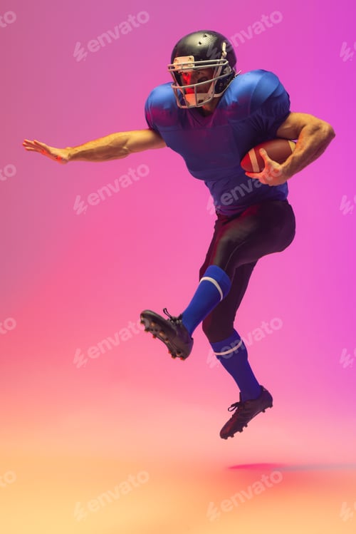 Preview: Caucasian male american football player holding ball with neon pink lighting
