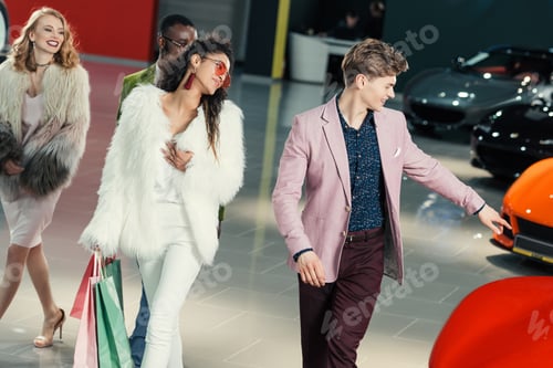 Preview: group of young shoppers walking by showroom and choosing car