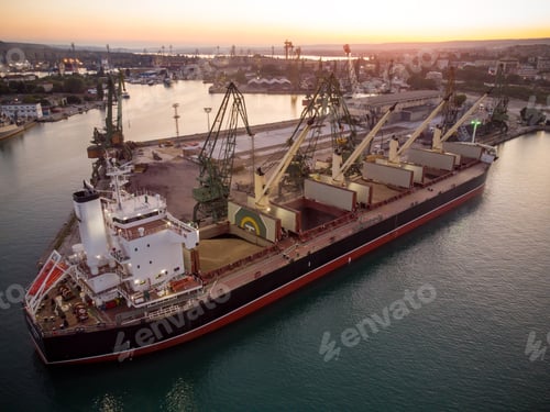 Preview: Aerial view of big cargo ship bulk carrier is loaded with grain of wheat in port at sunset