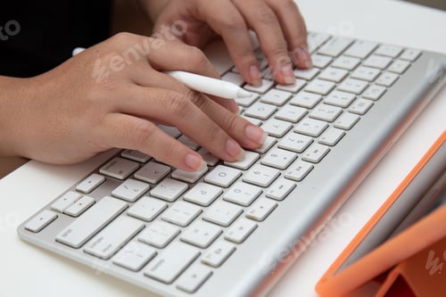 Preview: Person with a pen typing on a wireless keyboard with a digital tablet