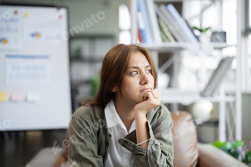 Preview: Young Asian woman working on laptop computer looking away thinking