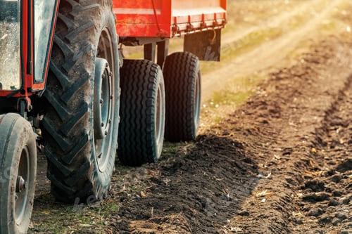 Preview: Old red agricultural tractor with trailer on dirt countryside ro