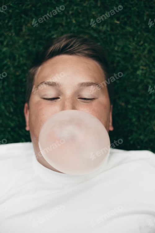 Preview: Portrait of teenage boy blowing bubble gum bubble