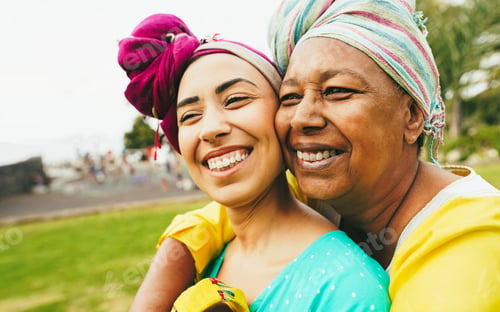 Preview: Happy african mother and daughter wearing traditional clothes while having fun together outdoor