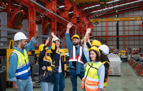 Preview: Group of factory workers in hardhats with arms raised celebrating success