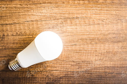 Preview: Energy saving light bulb on wooden table. Led Lightbulb. Top view.