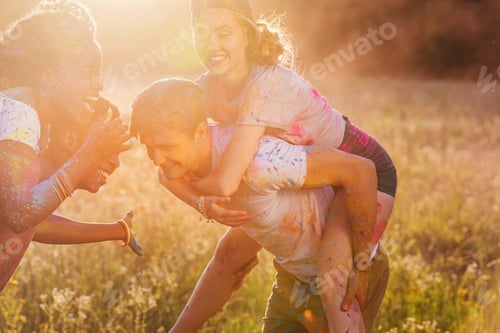 Preview: happy multiethnic couples piggybacking together at holi festival