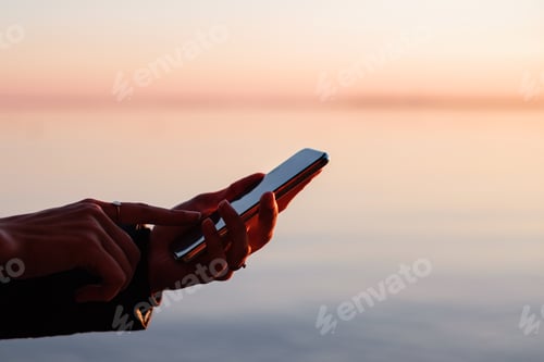 Preview: Using mobile device at sunset