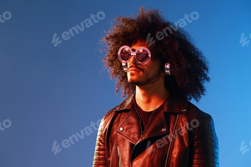 Preview: Portrait of a stylish man with curly hair with glasses and headphones on a blue background