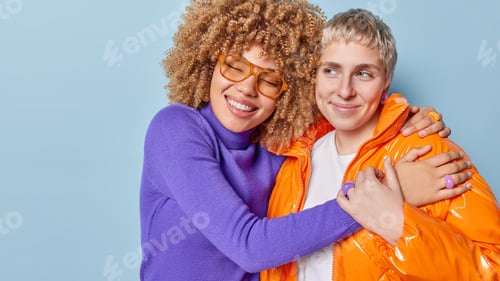 Preview: Two positive young female friends embrace and have fun together dressed in fashionable clothes love