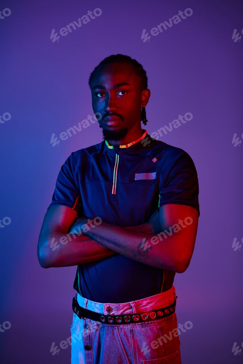 Preview: Stylish young African American man poses confidently under vibrant neon studio lights