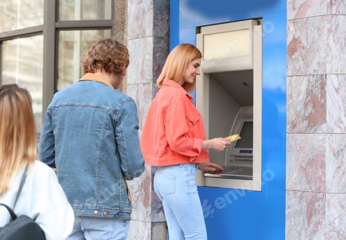 Preview: People standing in queue to cash machine outdoors