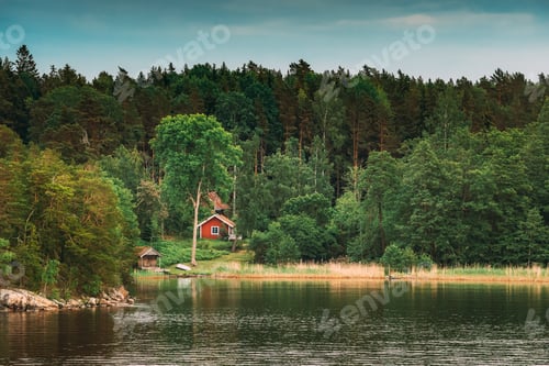 Preview: Sweden. Beautiful Red Swedish Wooden Log Cabin House On Rocky Island Coast In Summer. Lake Or River