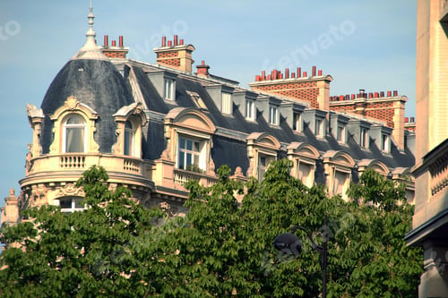 Preview: Ornate European building with slate roof and green trees.