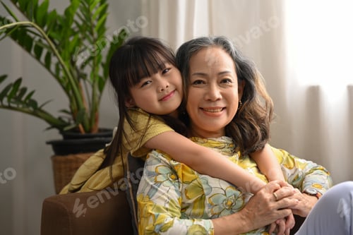 Preview: Cute little grandchild hugging her grandmother and smiling at camera. Family and love concept.