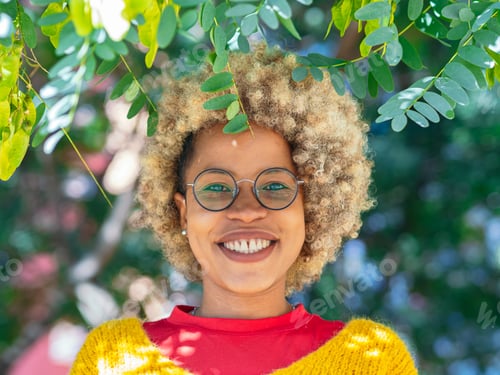 Preview: African American woman with afro hair and glasses among the greenery