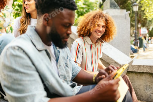 Preview: College students collaborating on a project using laptop outdoors