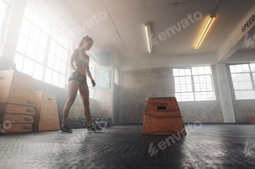 Preview: Muscular young woman working out with a box at crossfit gym