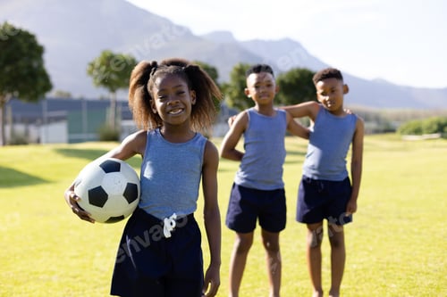 Preview: Portrait of happy african american schoolchildren playing football on field at school
