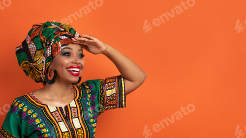 Preview: Cheerful black woman in african costume looking at copy space