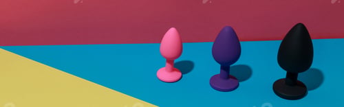 Preview: Different buttplugs and dildos for anal sex on colored background with shadows. Sex shop concept