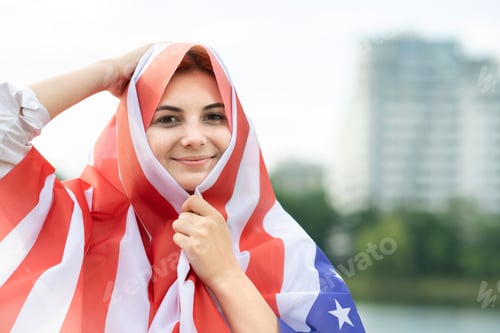 Preview: Portrait of young happy refugee woman with USA national flag on her head