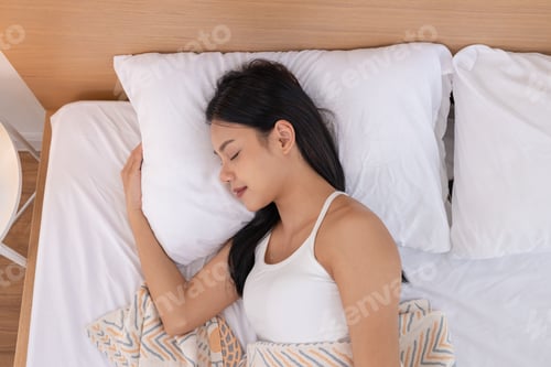 Preview: Peaceful woman sleeping in bed with white pillow