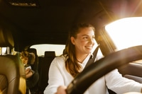 Preview: Young woman fastening her seat belt while sitting in car