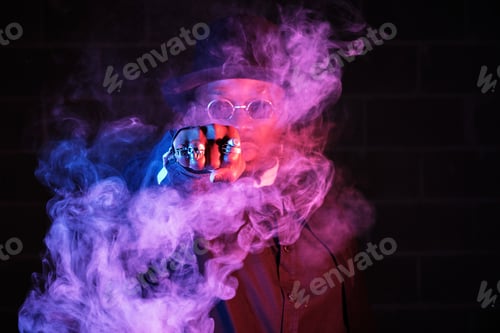 Preview: Stylish African American man surrounded by vapor in darkness