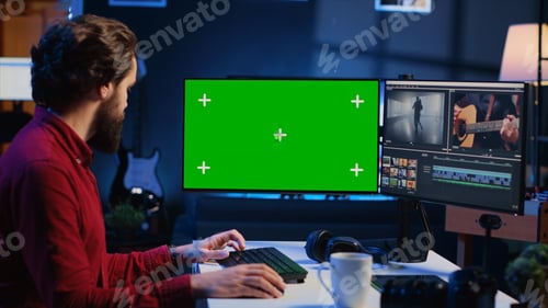 Preview: Videographer uses editing software on green screen computer to assemble footage