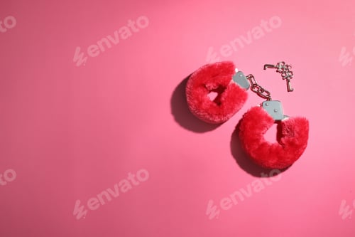 Preview: Red furry handcuffs and keys on pink background, flat lay with space for text. Sex toy