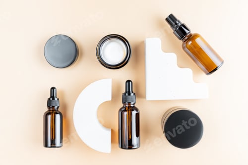 Preview: Set of skin care products in dark glass bottles on beige background with concrete podiums