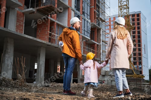 Preview: Family with child standing outdoors near building under construction.