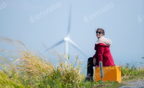 Preview: On the background of windmills, A young woman in a red jacket is enjoying her winter vacation.