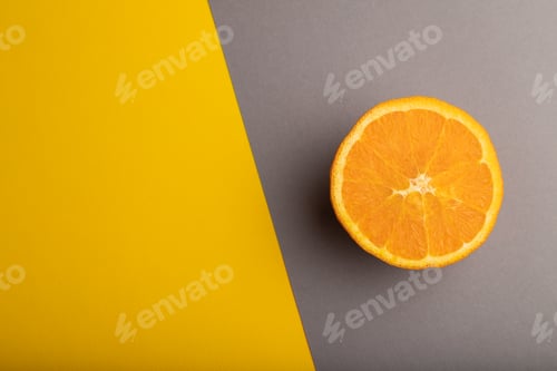 Preview: Ripe cut orange on gray and yellow pastel background. Top view, copy space.