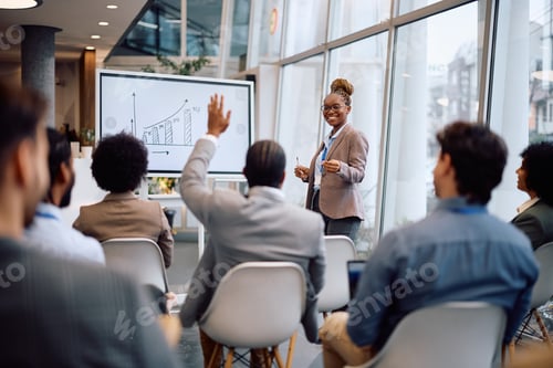 Preview: Black businesswoman aiming at one of colleagues who wants to ask a question during a conference.
