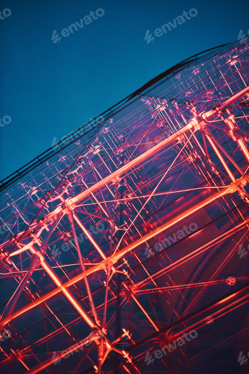 Preview: Looking up at modern glass building lighted with red at night