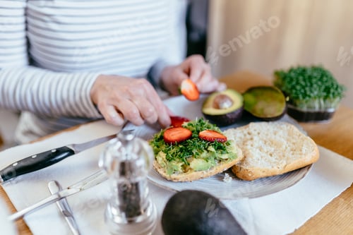 Preview: Adding strawberry slices on avocado toast healthy breakfast concept