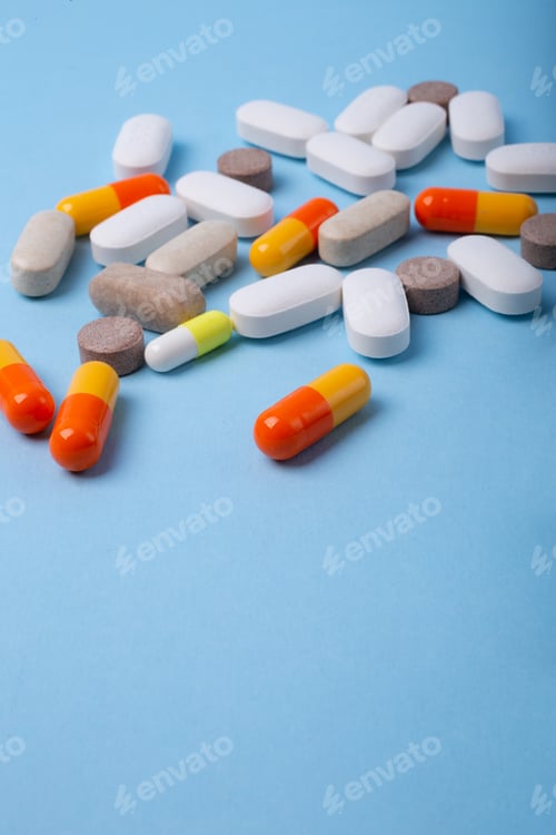 Preview: Vertical photography of different pills on blue background with negative space.