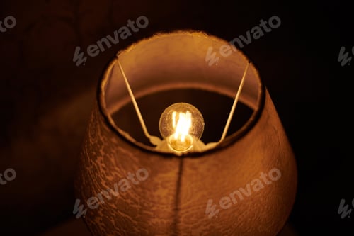 Preview: Incandescent lamp in round lampshade glowing in dark.