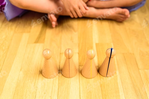 Preview: Girl sitting on the floor in front of a set of montessori material to learn fractions.